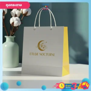 ถุงกระดาษ สีขาวและเหลืองของแบรนด์ Etude Nocturne พร้อมโลโก้รูปพระจันทร์เสี้ยว ดาว และโน้ตดนตรีสีทอง